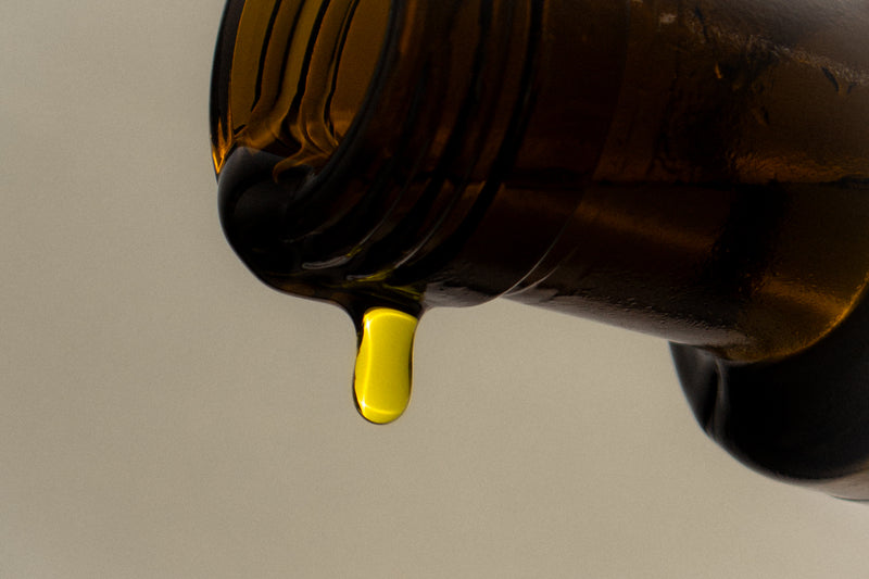 Close-up of a bottle cap with a drop of yellow liquid on a beige background